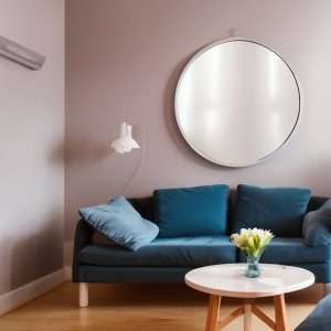 a round mirror is hanging above a blue sofa