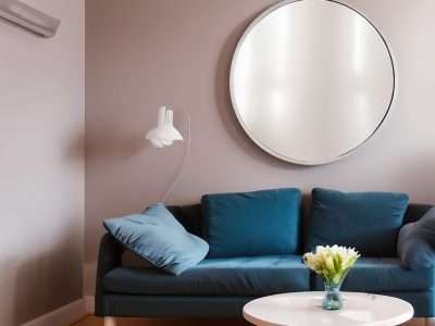 a round mirror is hanging above a blue sofa