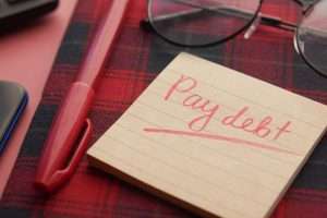 pay debt written on a piece of paper beside a red pen