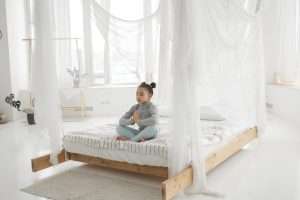 Cute little girl meditating on the bed during yoga practice